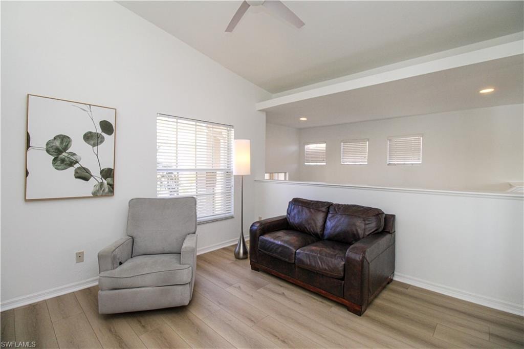 Sitting room with lofted ceiling, ceiling fan, and light wood-type flooring