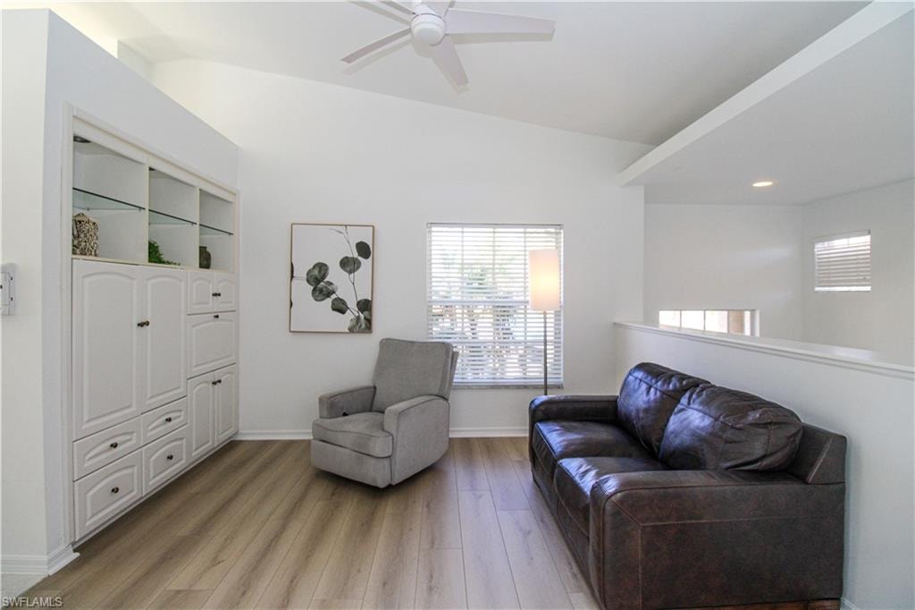 Sitting room with ceiling fan, vaulted ceiling, and light wood-type flooring