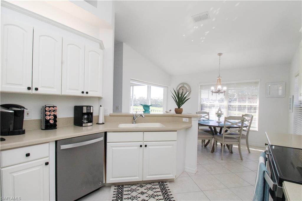 Kitchen with white cabinets, dishwasher, sink, and decorative light fixtures