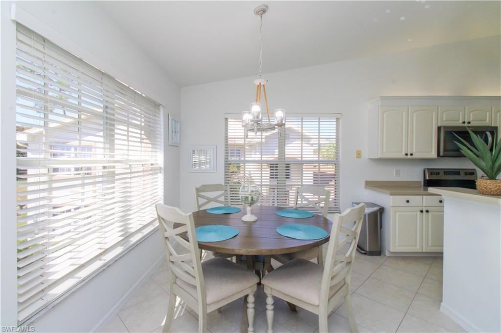 Dining room with a wealth of natural light, light tile patterned flooring, a chandelier, and vaulted ceiling