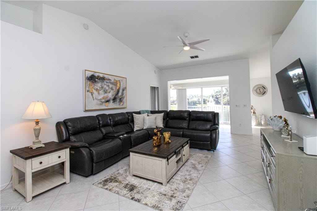 Tiled living room with ceiling fan and lofted ceiling