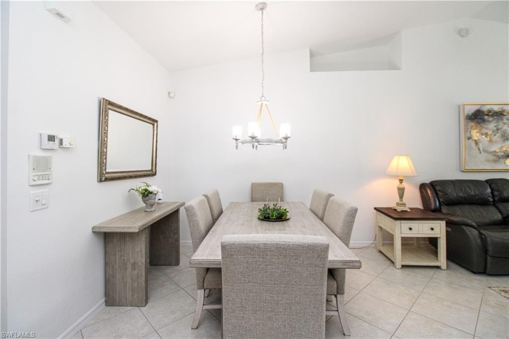 Tiled dining room with an inviting chandelier and vaulted ceiling