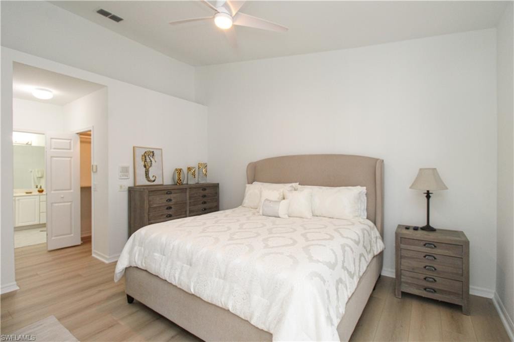 Bedroom with ceiling fan, light wood-type flooring, and connected bathroom
