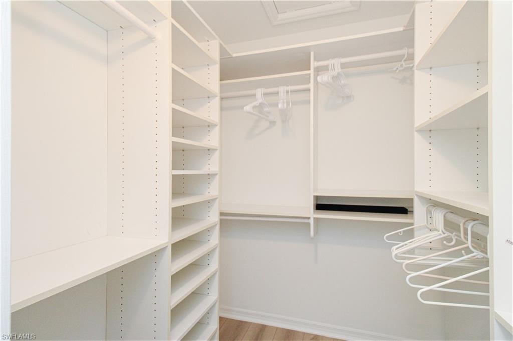 Walk in closet with light hardwood / wood-style floors