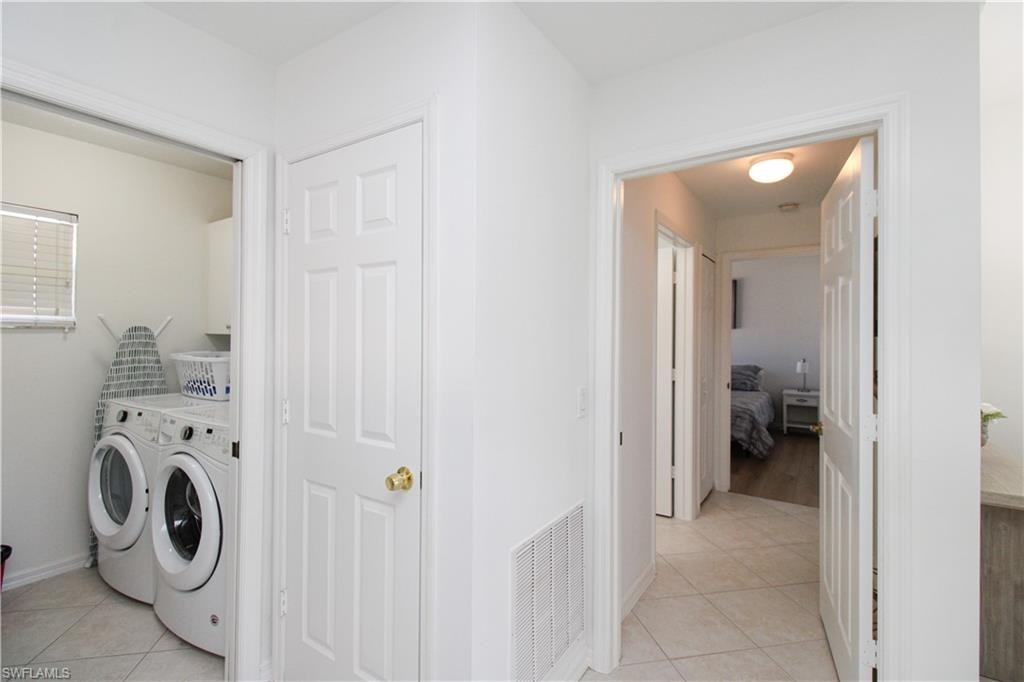 Washroom with independent washer and dryer and light tile patterned flooring