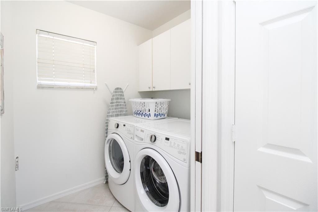 Laundry area featuring light tile patterned floors, cabinets, and independent washer and dryer