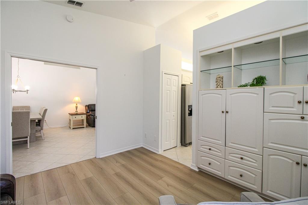Bedroom featuring stainless steel refrigerator with ice dispenser, light wood-type flooring, and a notable chandelier