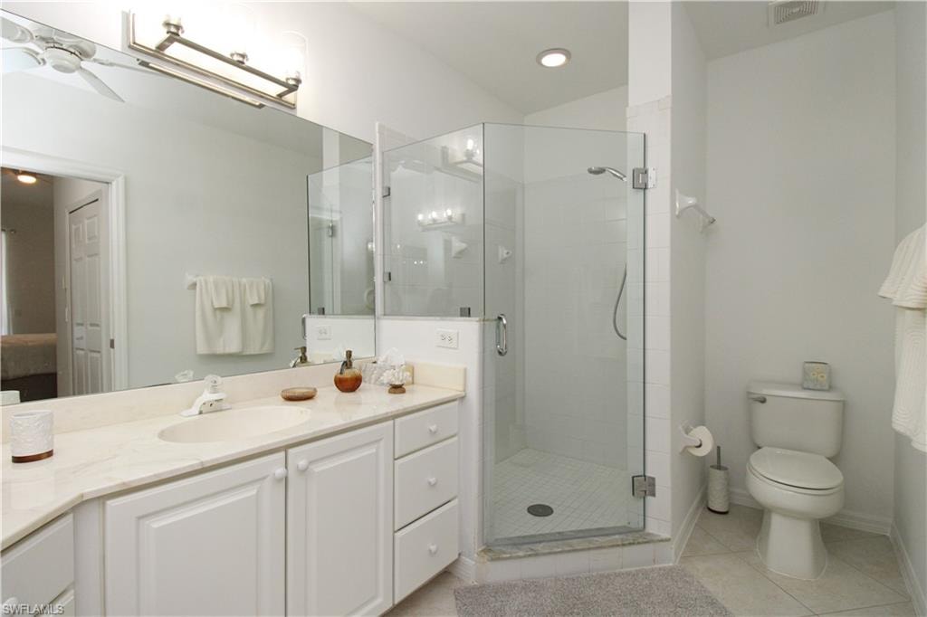 Bathroom featuring tile patterned floors, toilet, vanity, and walk in shower