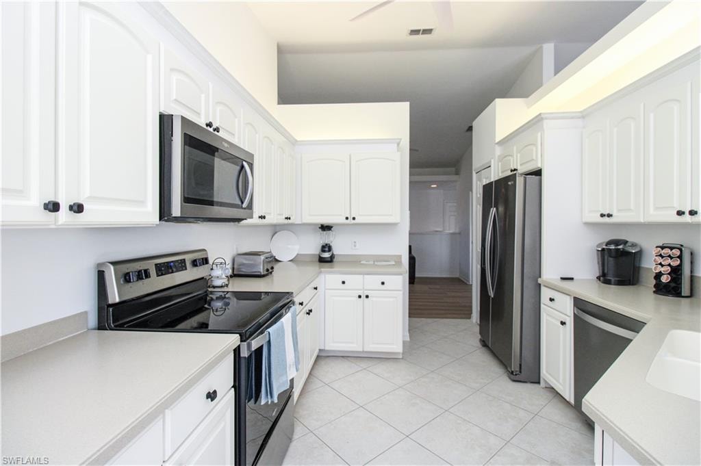 Kitchen featuring white cabinetry, light tile patterned floors, and appliances with stainless steel finishes