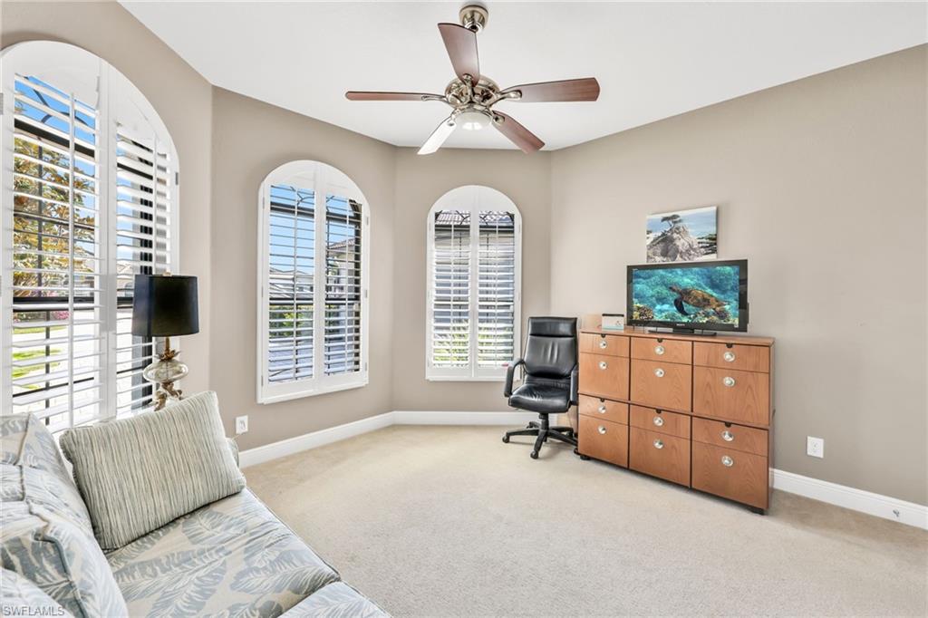 Home office with a ceiling fan and light colored carpet