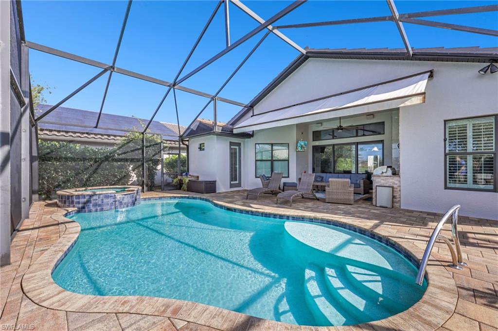 View of pool featuring glass enclosure, an outdoor hangout area, a patio, and a sunroom
