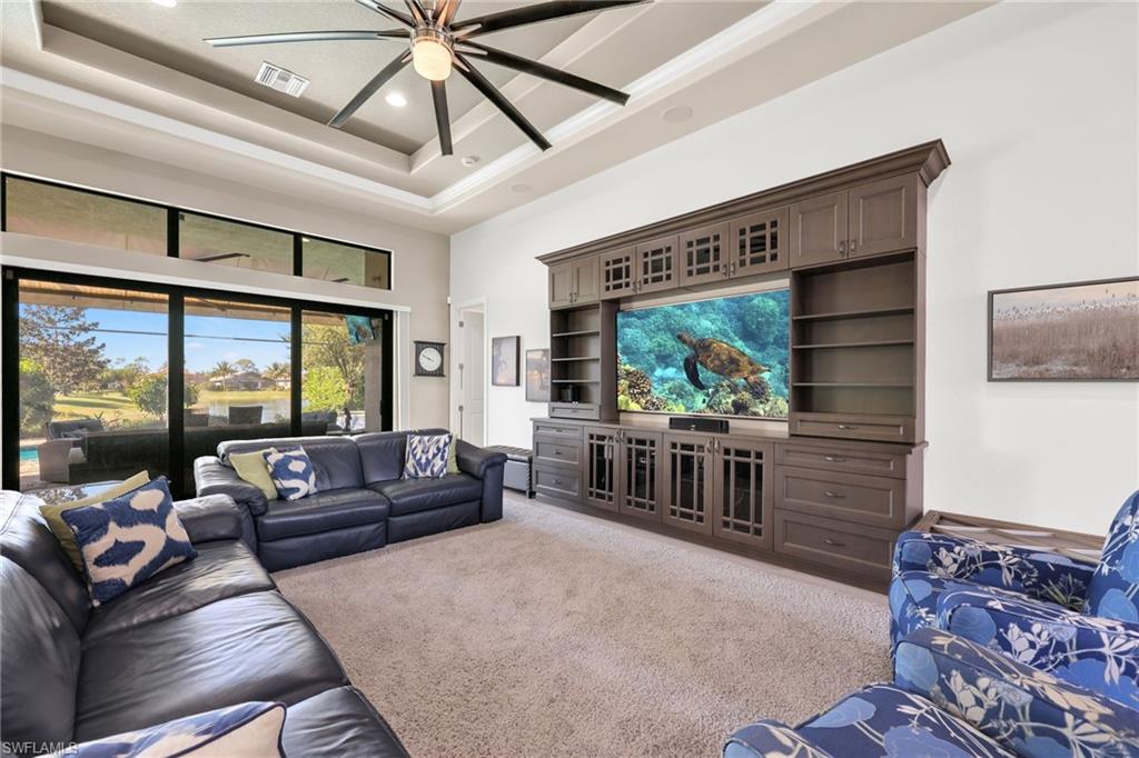 Living area featuring a towering ceiling, a tray ceiling, ceiling fan, recessed lighting, and carpet