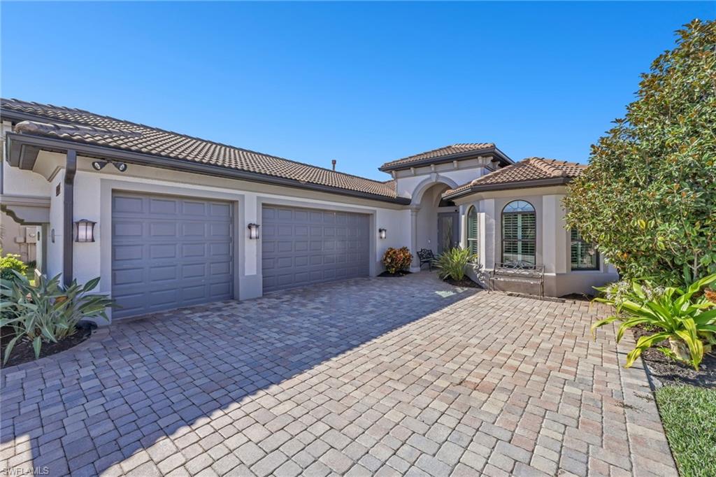 Mediterranean / spanish home with stucco siding, decorative driveway, an attached garage, and a tiled roof