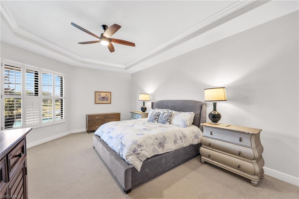 Bedroom featuring a raised ceiling, a ceiling fan, light colored carpet, and crown molding