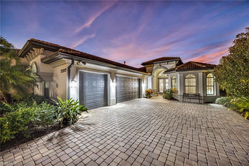 View of front facade with stucco siding, decorative driveway, a garage, and french doors