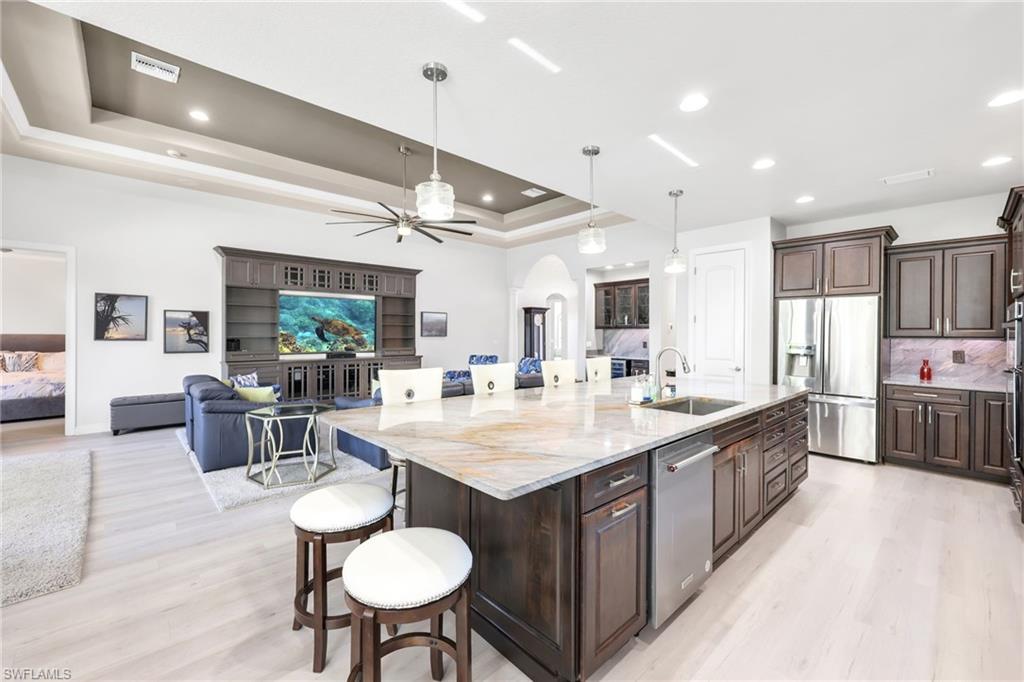 Kitchen with a breakfast bar area, dark brown cabinets, arched walkways, a ceiling fan, and a large island