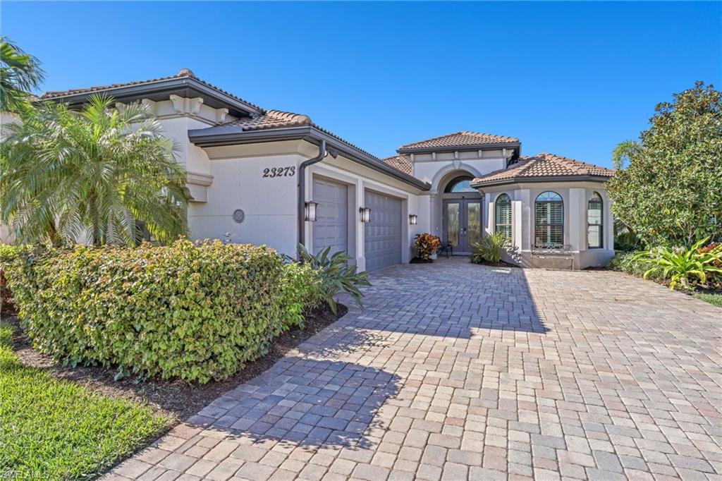Mediterranean / spanish house with a garage, stucco siding, decorative driveway, a tiled roof, and french doors