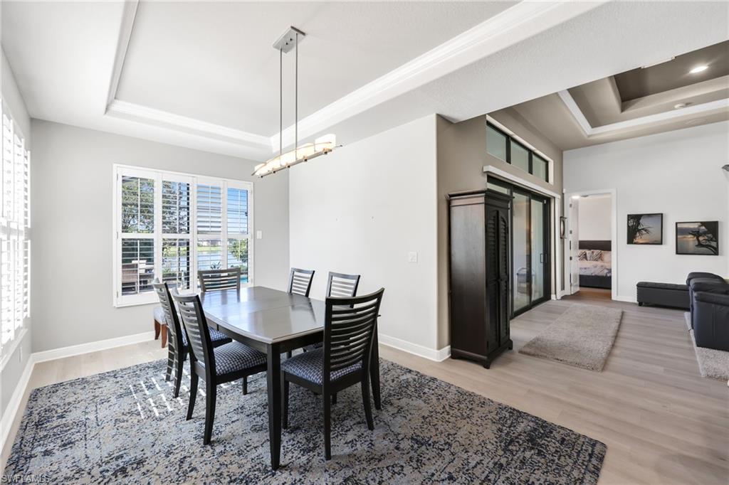 Dining room featuring a tray ceiling, light wood-style flooring, and a chandelier