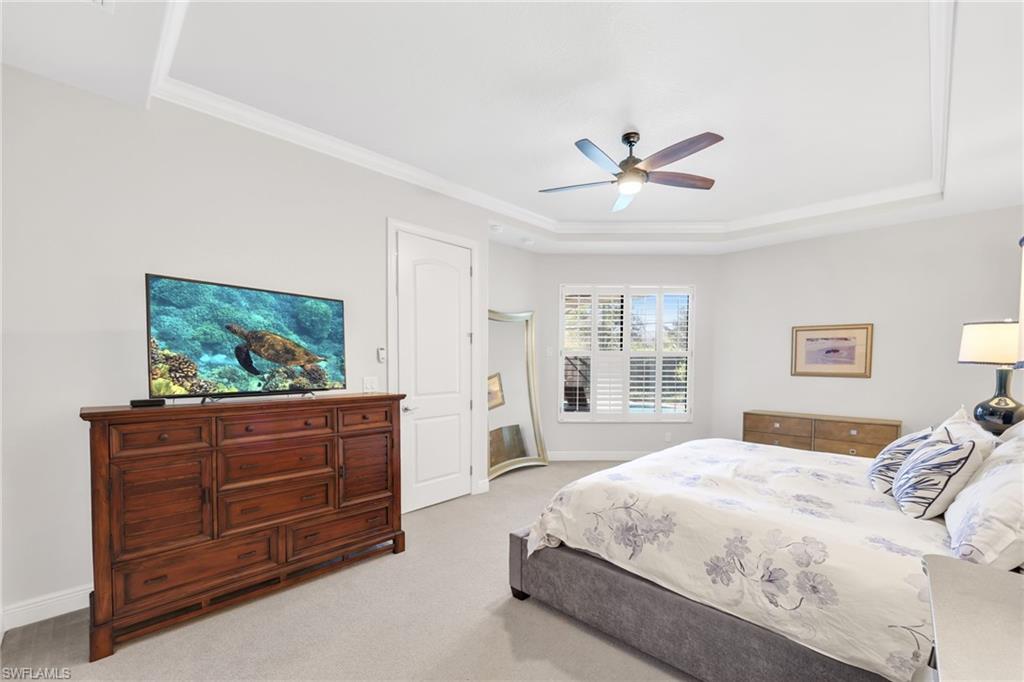 Bedroom featuring light carpet, a ceiling fan, crown molding, and a raised ceiling
