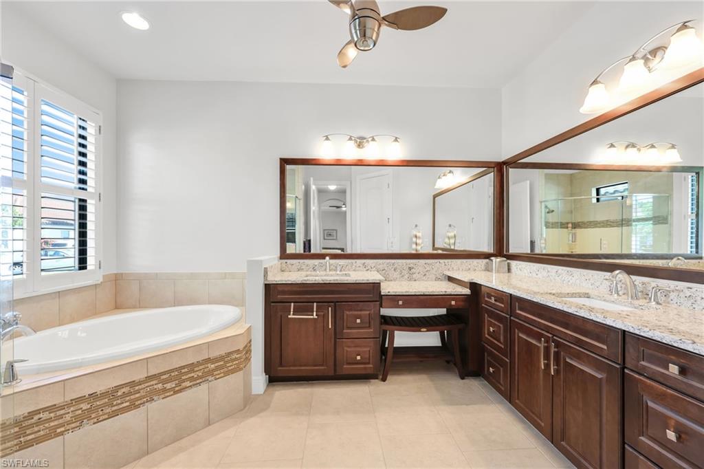 Full bathroom featuring double vanity, a bath, a ceiling fan, a stall shower, and light tile patterned flooring