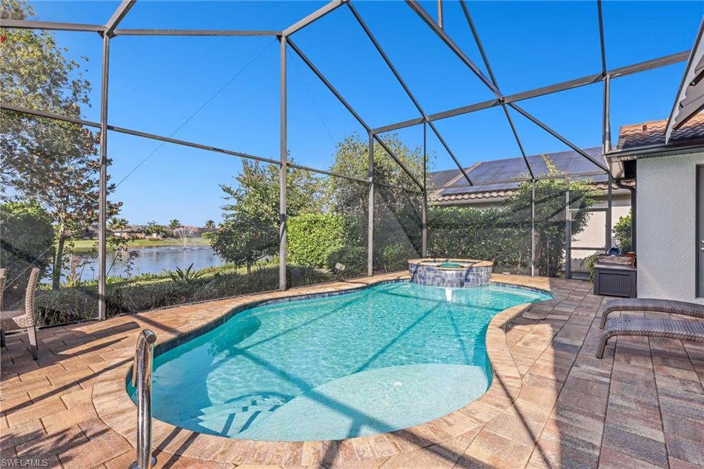 View of swimming pool with glass enclosure, a sunroom, a pool with connected hot tub, and a patio