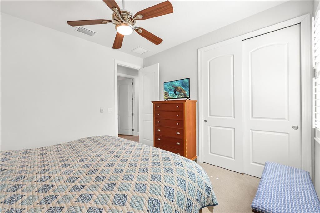 Bedroom with a closet, light carpet, and a ceiling fan