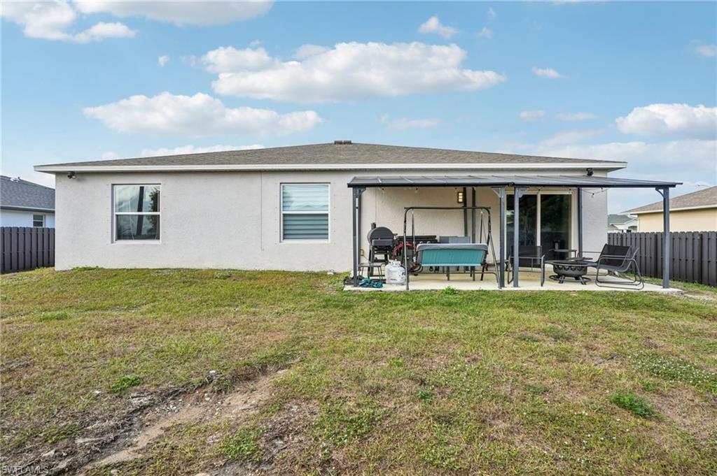 Back of property featuring a fenced backyard, a patio, stucco siding, and roof with shingles