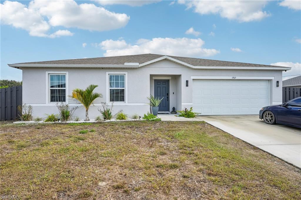 Ranch-style home featuring stucco siding, a front lawn, concrete driveway, and an attached garage