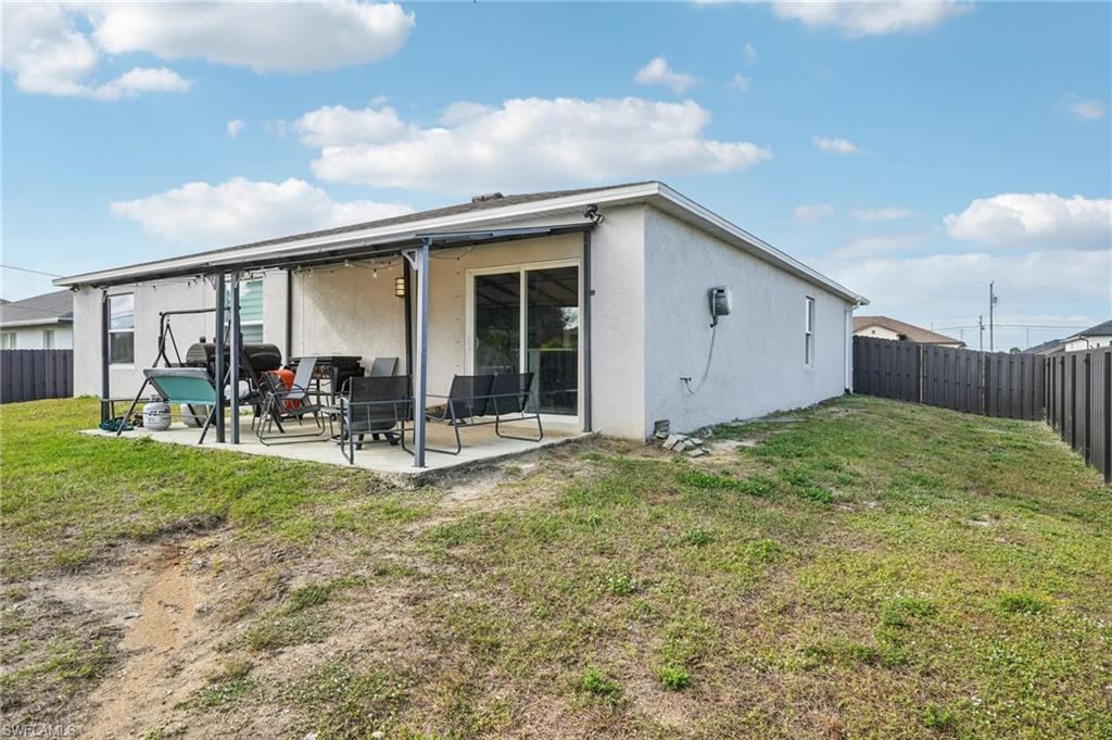 Back of property with a fenced backyard, stucco siding, and a patio