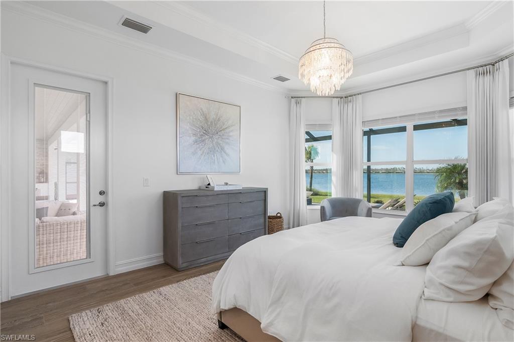 Bedroom with a water view, crown molding, wood finished floors, a chandelier, and access to exterior