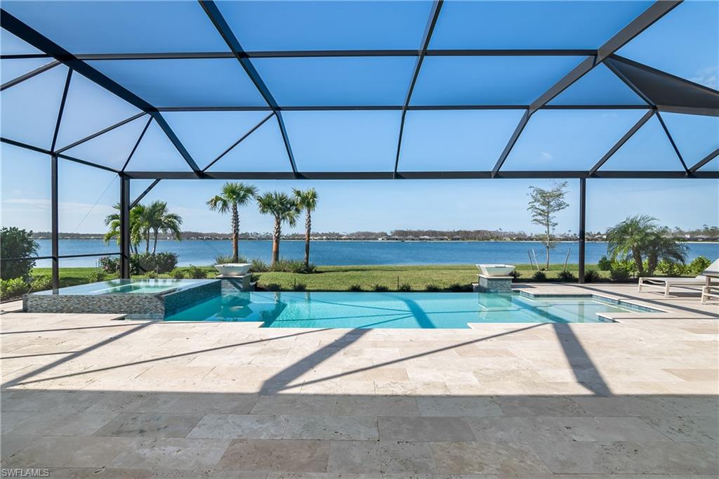 View of pool featuring a pool with connected hot tub, glass enclosure, a water view, a patio, and a sunroom