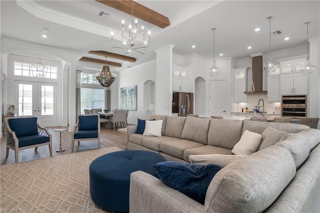 Living area with arched walkways, beamed ceiling, crown molding, wood finished floors, and recessed lighting