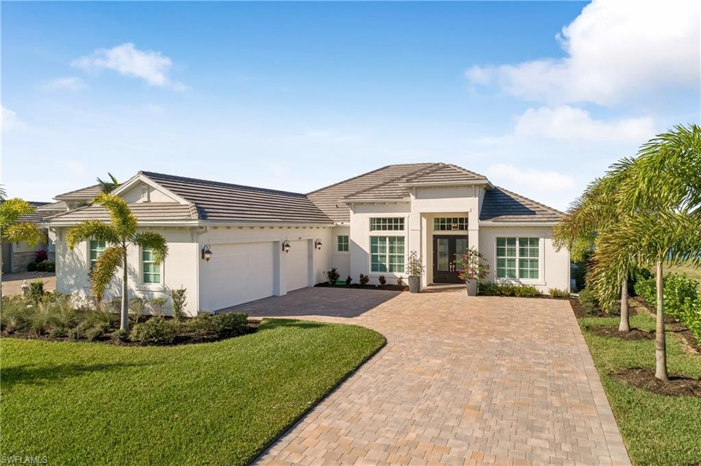 View of front of home with a garage, stucco siding, decorative driveway, and a front yard