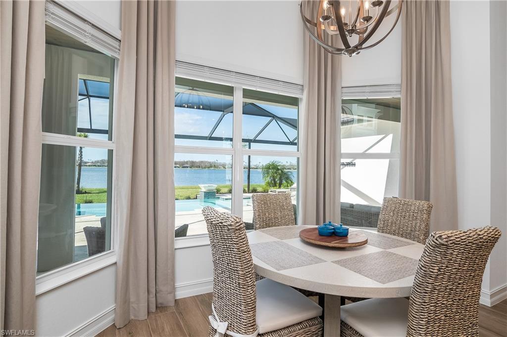 Dining room featuring a water view, wood finished floors, a chandelier, a sunroom, and plenty of natural light