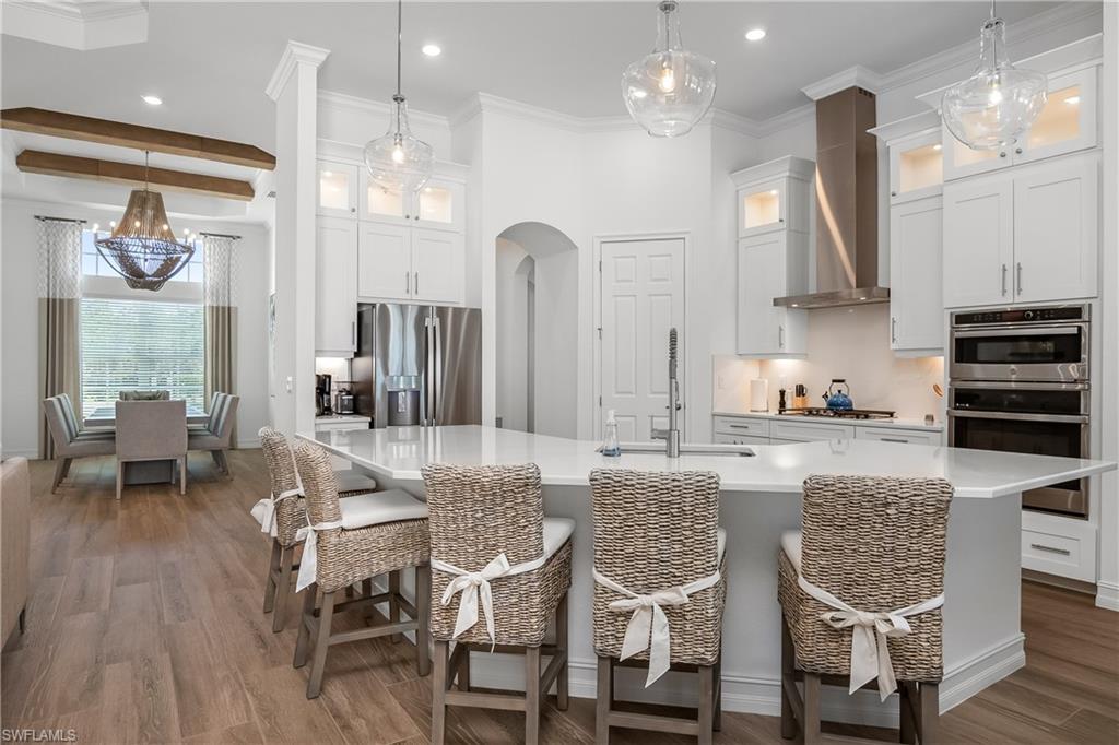 Kitchen featuring decorative light fixtures, a kitchen bar, crown molding, white cabinets, and stainless steel appliances