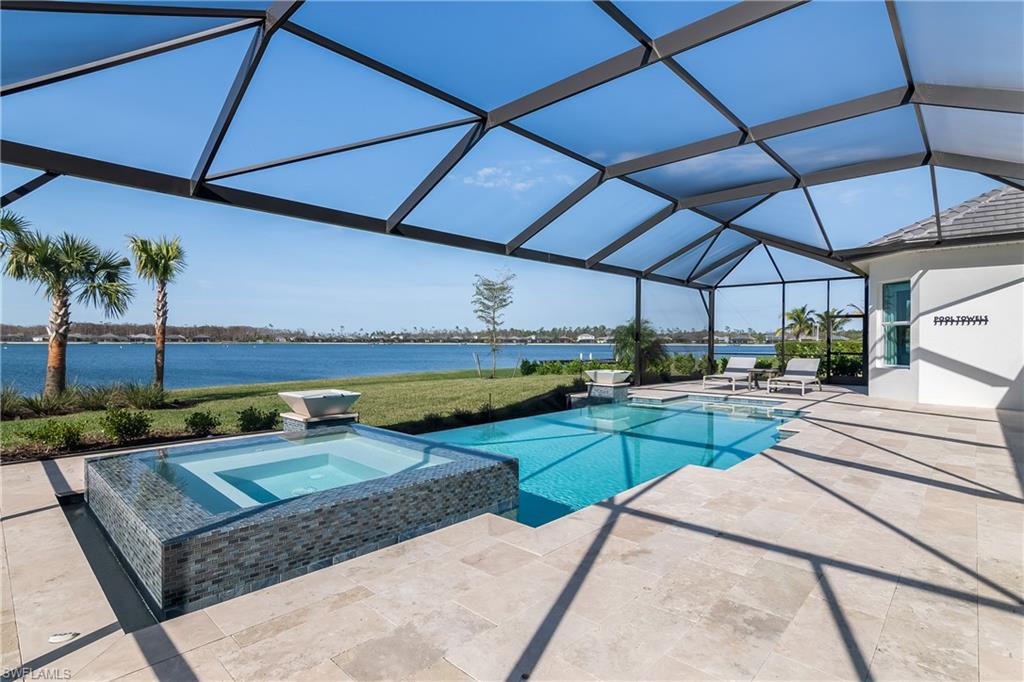 View of pool featuring a pool with connected hot tub, a patio area, a water view, glass enclosure, and a sunroom