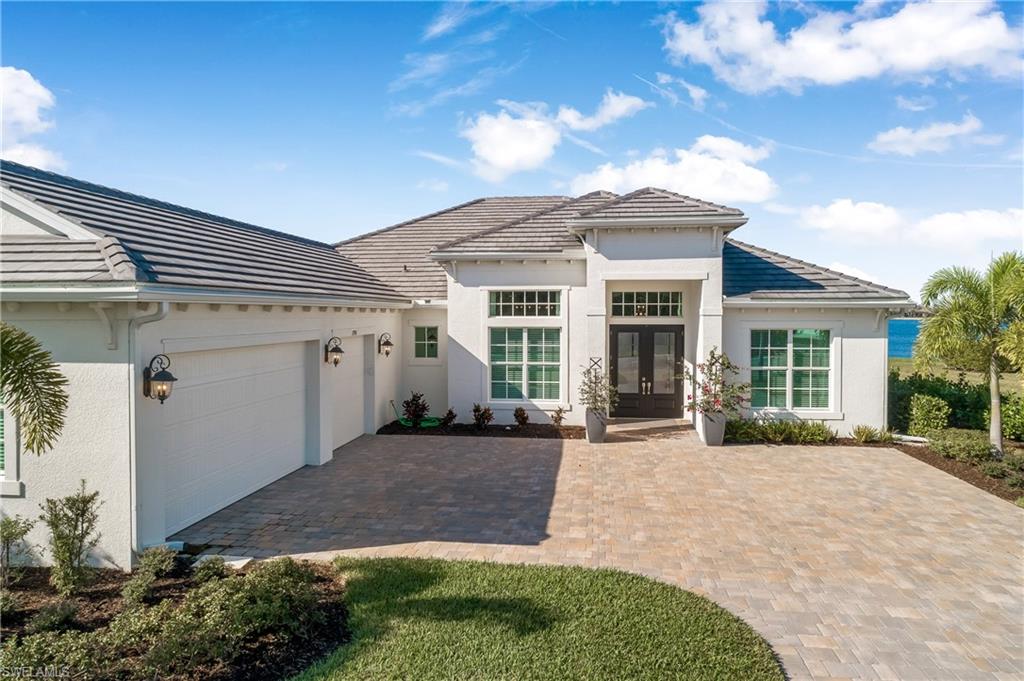 View of front of property with french doors, stucco siding, an attached garage, and driveway