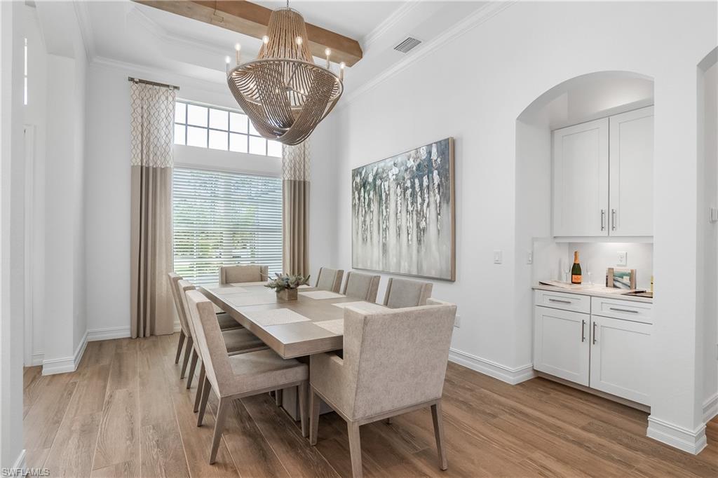 Dining room with beamed ceiling, crown molding, light wood finished floors, and a chandelier