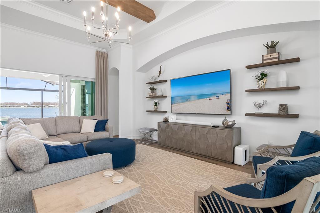 Living room with a water view, wood finished floors, ornamental molding, and a high ceiling