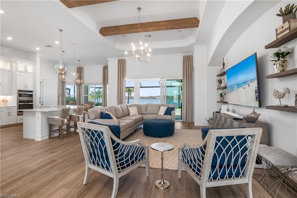 Living room featuring a chandelier, crown molding, light wood-style flooring, and beamed ceiling