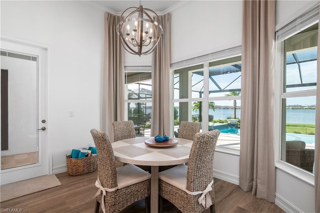 Dining room with a water view, a chandelier, dark wood-style floors, and crown molding