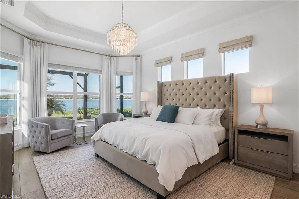 Bedroom featuring ornamental molding, a water view, multiple windows, a chandelier, and wood finished floors