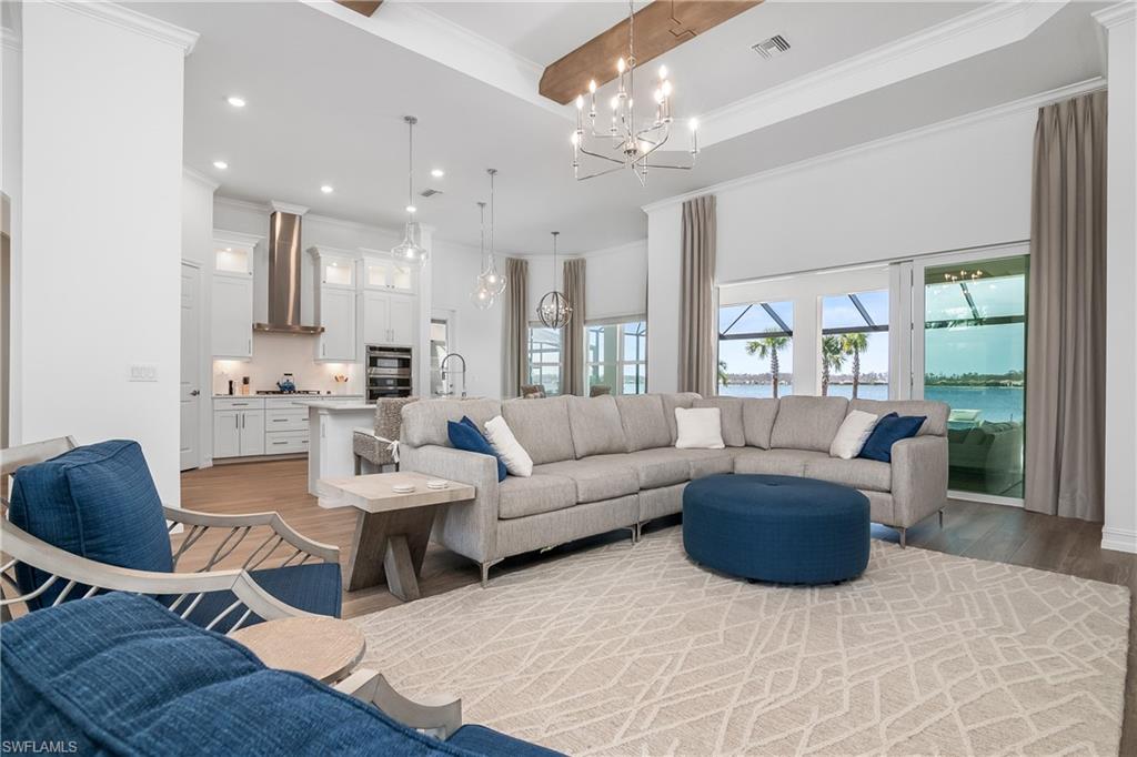 Living area with crown molding, a water view, recessed lighting, a chandelier, and light wood finished floors