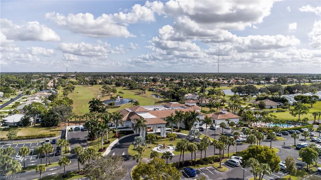 Aerial view of property and surrounding area with a golf course, a large body of water, and nearby suburban area