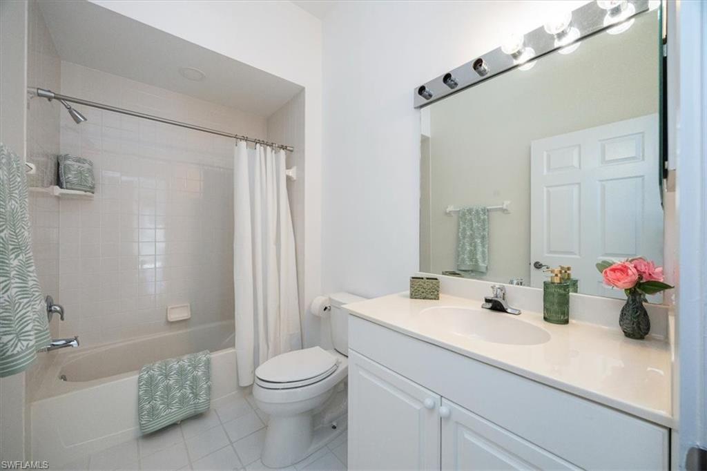 Full bathroom with vanity, toilet, tile patterned floors, and shower / bath combination with curtain
