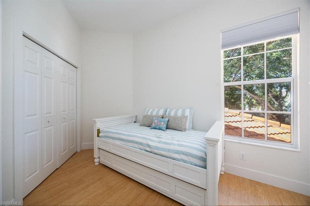 Bedroom featuring multiple windows, hardwood / wood-style floors, and a closet