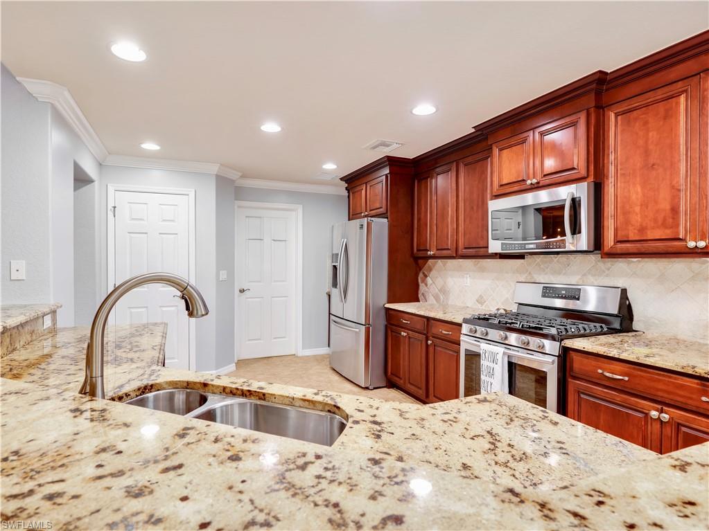 Kitchen with appliances (gas stove)  with stainless steel finishes, light stone countertops, crown molding, tasteful backsplash, and recessed lighting