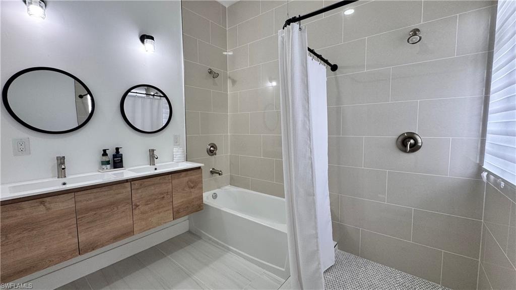 Bathroom featuring double vanity, tile patterned floors, and tiled shower / bath