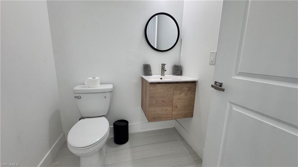 Half bath featuring vanity and baseboards
