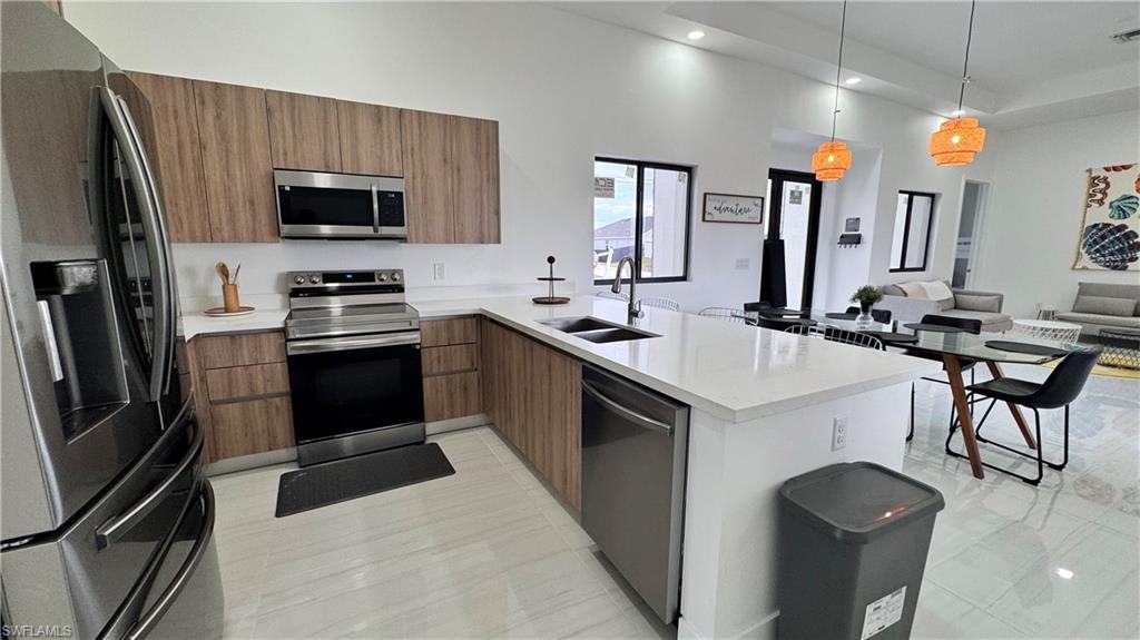 Kitchen featuring appliances with stainless steel finishes, modern cabinets, open floor plan, pendant lighting, and recessed lighting